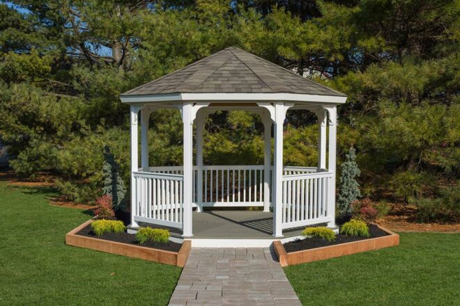 White vinyl octagon gazebo at the end of a stone pathway.